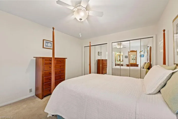 Bedroom featuring ceiling fan, two closets, and light carpet