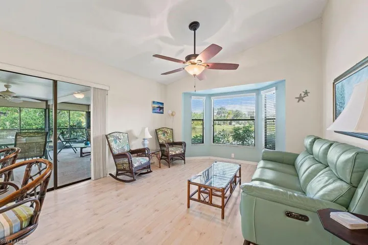 Living room featuring ceiling fan, light hardwood / wood-style flooring, vaulted ceiling, and plenty of natural light