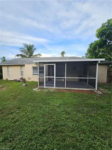 Back of property with a lawn and a sunroom