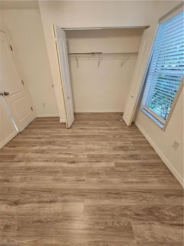 Unfurnished bedroom featuring multiple windows, light hardwood / wood-style flooring, and a closet