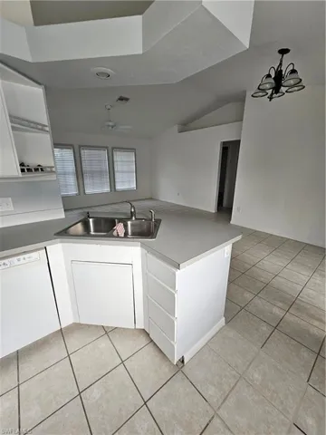 Kitchen with white cabinets, light tile patterned floors, sink, and ceiling fan