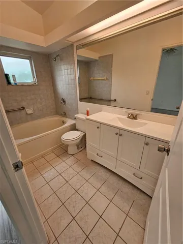 Full bathroom featuring tiled shower / bath, vanity, toilet, and tile patterned flooring