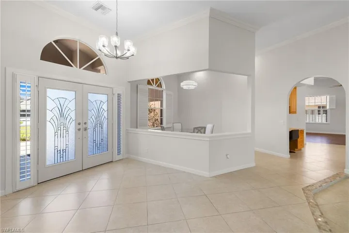 Spacious entryway featuring double-door entry with decorative glass, an arched transom window, and tile flooring