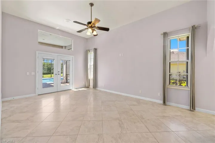 Primary bedroom #1, spacious interior featuring a light-toned tile floor, vaulted ceiling, and ceiling fan