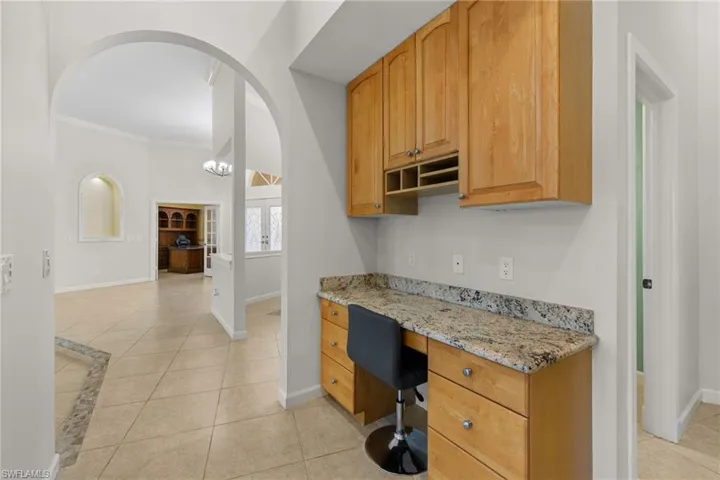 Built-in desk area featuring a granite-look countertop and wood cabinetry with metal hardware