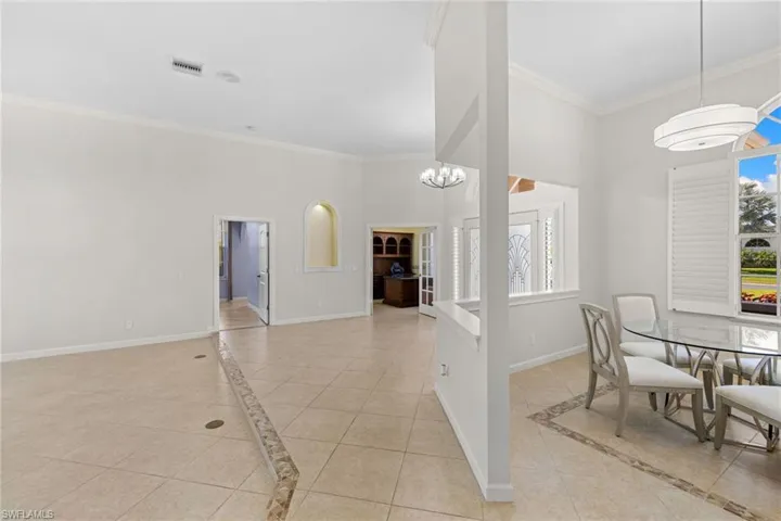 Bright interior with tiled flooring featuring an accent border, high ceilings with crown molding, and an arched wall niche