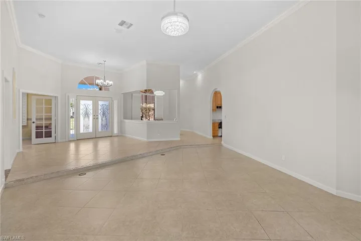 Spacious interior featuring neutral tile flooring, high vaulted ceilings, and crown molding