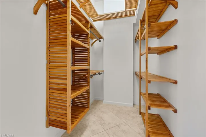 Primary bedroom #1 custom closet featuring natural wood-finish shelving and hanging rods