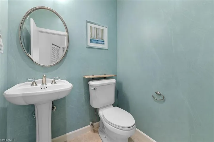 Half bathroom #3 featuring a pedestal sink, brushed nickel faucet, oval mirror, and light blue textured walls