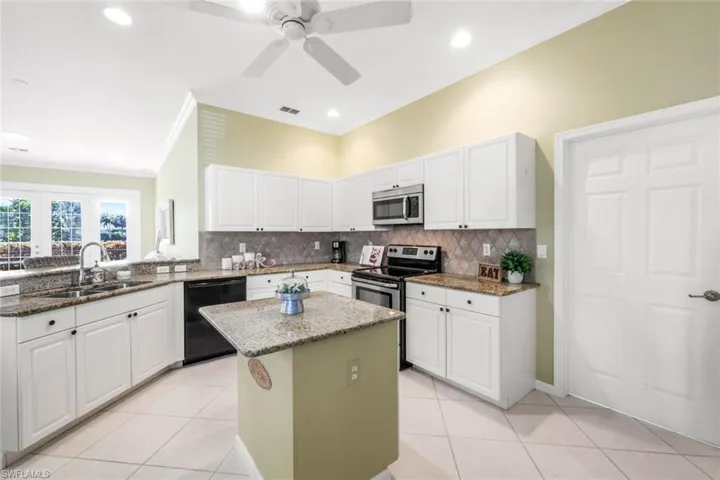 Kitchen with a kitchen island, white cabinetry, appliances with stainless steel finishes, and sink