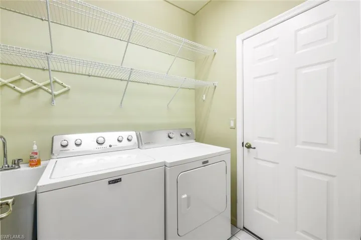 Laundry room featuring light tile patterned floors, washer and clothes dryer, and sink