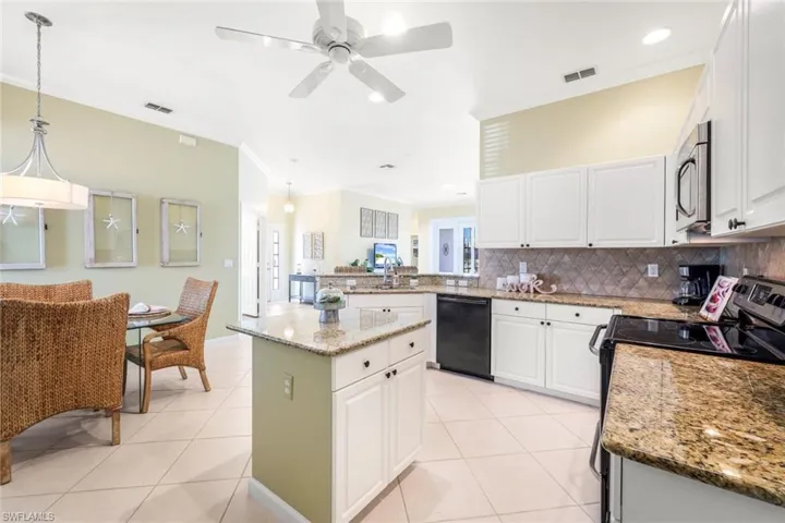 Kitchen with black appliances, kitchen peninsula, a kitchen island, pendant lighting, and white cabinets