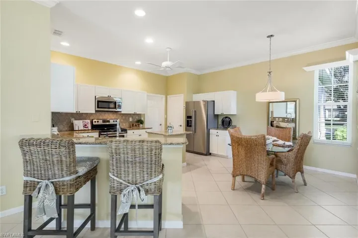 Kitchen with tasteful backsplash, hanging light fixtures, appliances with stainless steel finishes, kitchen peninsula, and white cabinets
