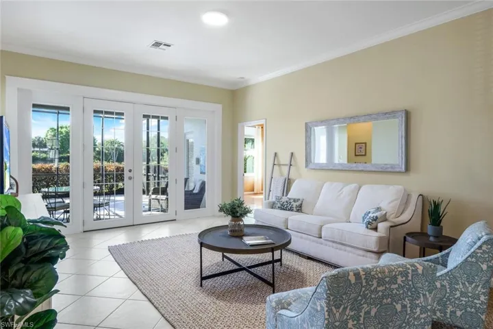 Tiled living room with crown molding and french doors
