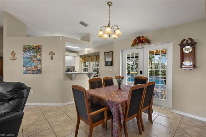 Dining room featuring light tile patterned floors, visible vents, vaulted ceiling, and french doors