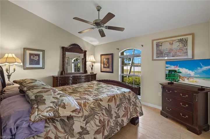 Bedroom with light wood-type flooring, lofted ceiling, baseboards, and a ceiling fan