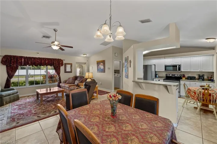 Dining room with lofted ceiling, light tile patterned flooring, visible vents, and baseboards