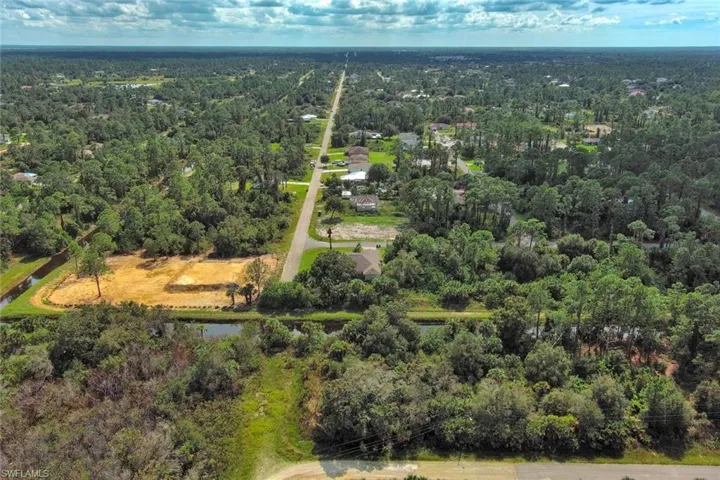 Drone / aerial view of a nearby body of water and a heavily wooded area