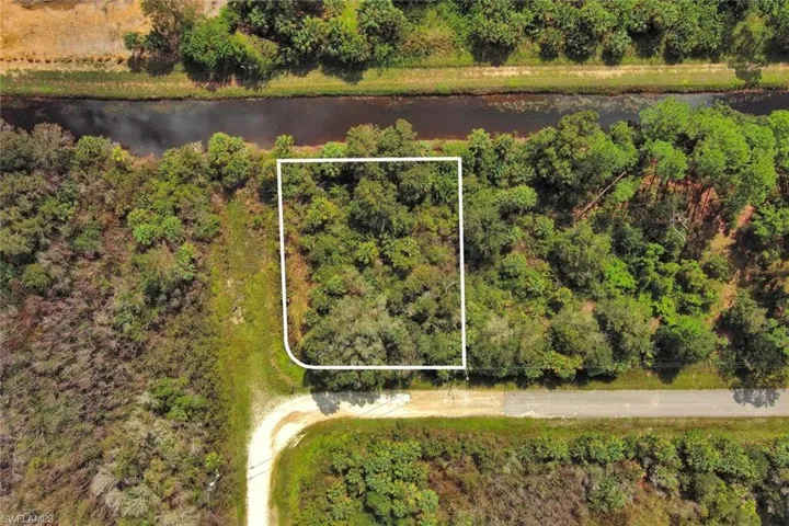 Aerial view of property and surrounding area featuring property boundaries highlighted and a large body of water