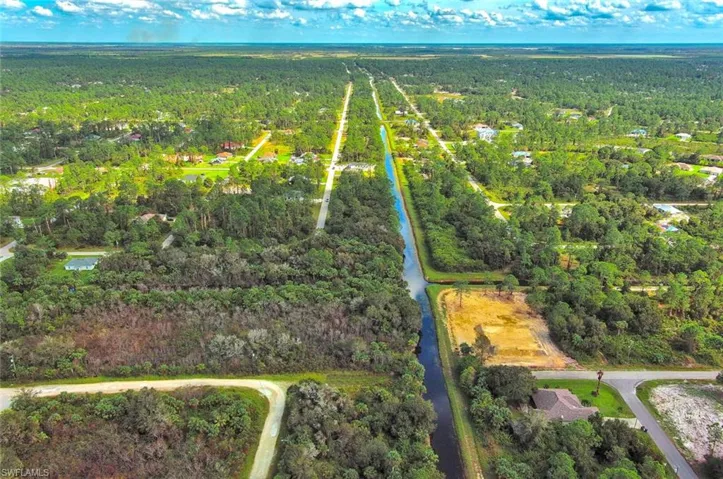Aerial overview of property's location featuring a heavily wooded area and a large body of water