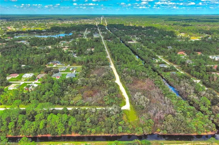 Aerial view of property's location with a large body of water and a forest