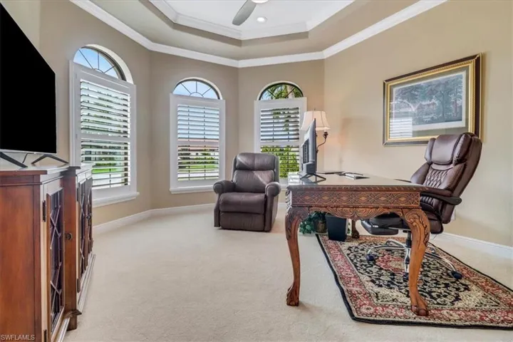 Carpeted home office with ceiling fan and crown molding