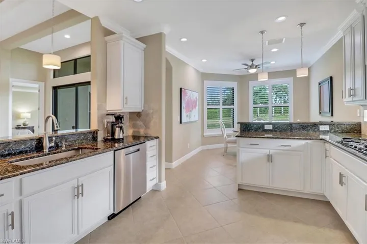 Kitchen with hanging light fixtures, white cabinetry, sink, and stainless steel appliances