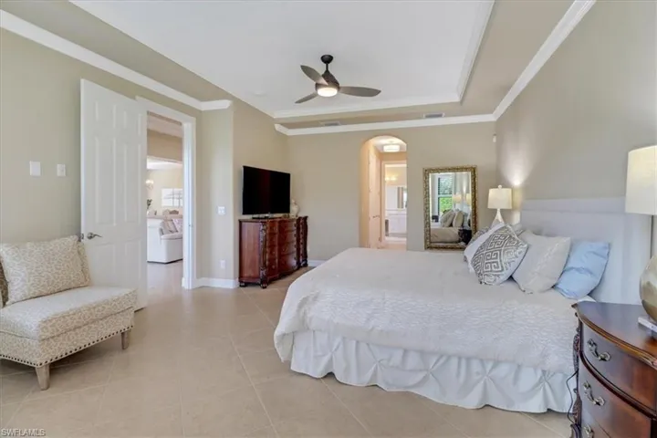 Bedroom with light tile patterned floors, ceiling fan, and crown molding