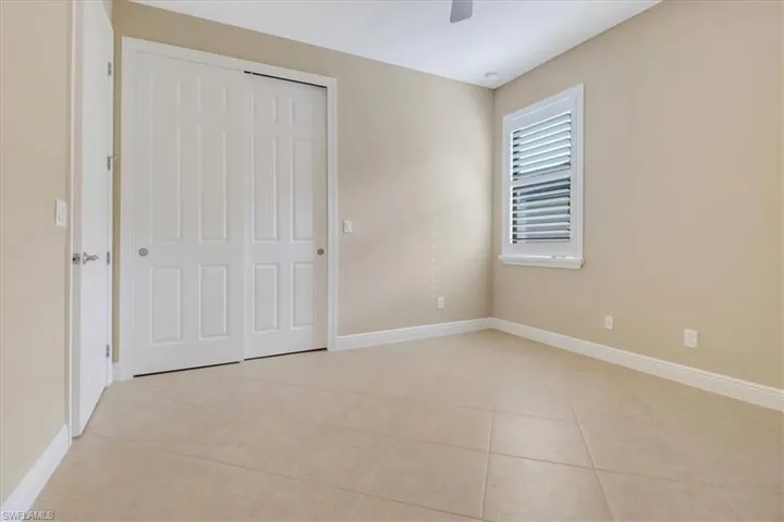 Unfurnished bedroom featuring a closet, ceiling fan, and light tile patterned flooring