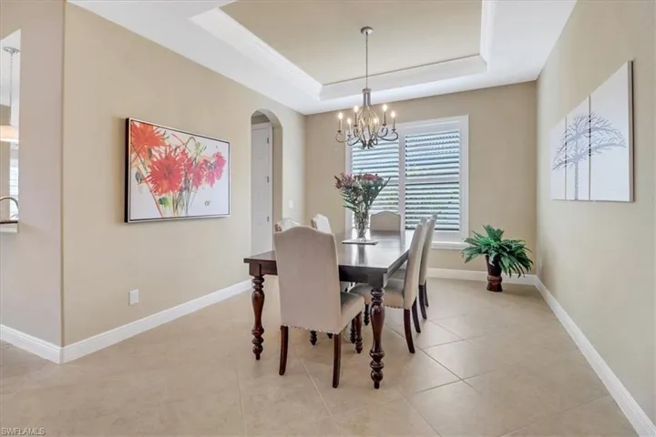 Dining area featuring an inviting chandelier, light tile patterned floors, crown molding, and a tray ceiling