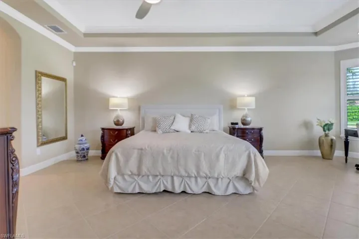 Tiled bedroom with ceiling fan and ornamental molding