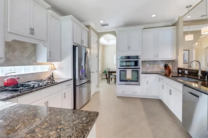 Kitchen with hanging light fixtures, white cabinetry, sink, and appliances with stainless steel finishes