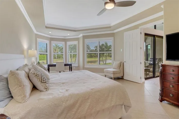 Bedroom featuring access to exterior, ceiling fan, a raised ceiling, light tile patterned floors, and ornamental molding