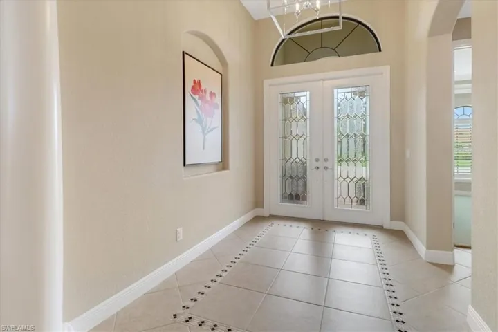 Tiled entryway with french doors and a notable chandelier