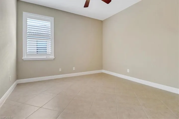 Tiled spare room featuring ceiling fan
