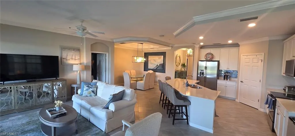 Living room featuring crown molding, arched walkways, a ceiling fan, recessed lighting, and light tile patterned floors