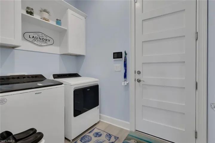 Laundry area featuring independent washer and dryer, light wood-style flooring, and cabinet space