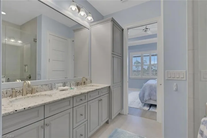 Bathroom with double vanity, a stall shower, ensuite bath, and a ceiling fan
