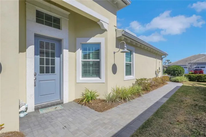 View of exterior entry with stucco siding and a lawn
