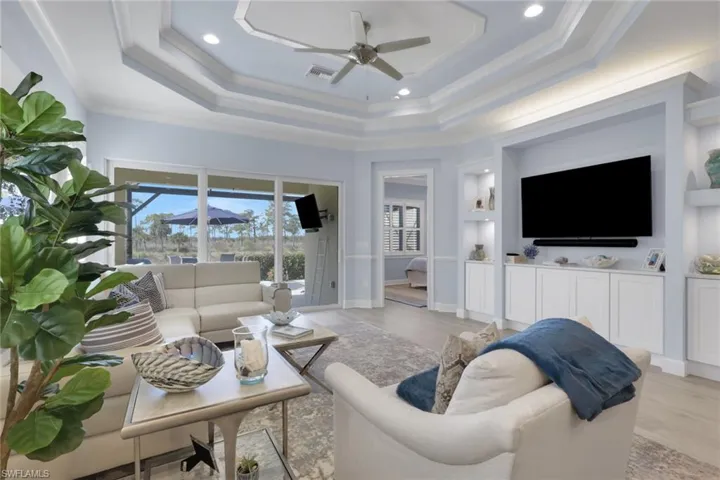 Living area featuring ceiling fan, wood finished floors, recessed lighting, built in shelves, and ornamental molding