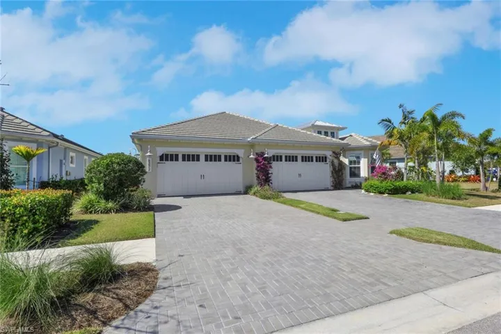 View of front of property with decorative driveway, a garage, stucco siding, and a tiled roof