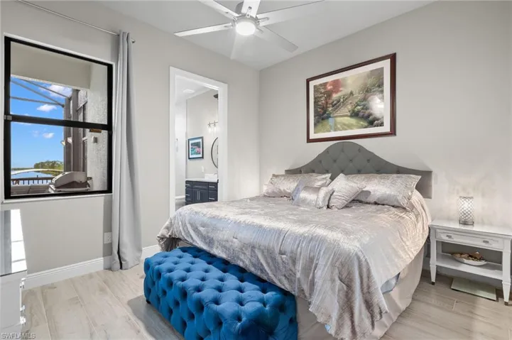 Bedroom with light wood-style flooring, a ceiling fan, and ensuite bathroom