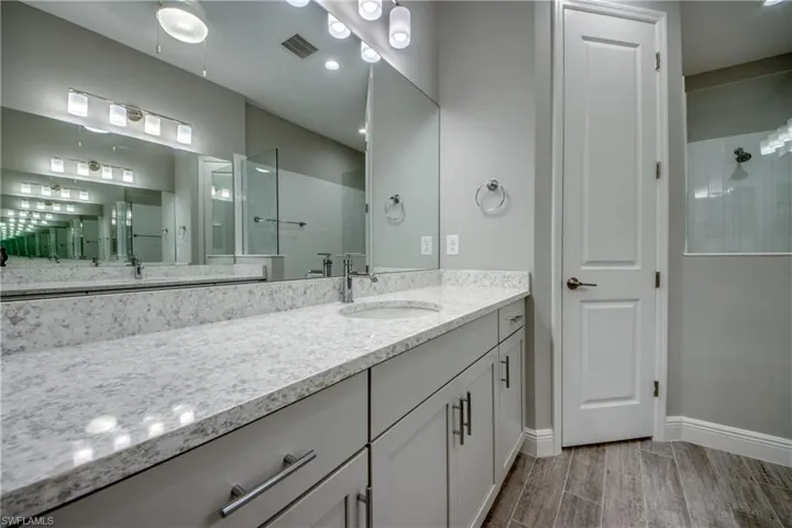 Double vanity featuring light-toned quartz countertop with integrated sinks, modern cabinetry, and chrome fixtures