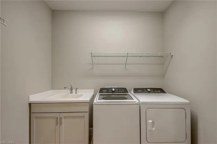 Spacious Laundry Room featuring a utility sink in cabinet and extra storage closet