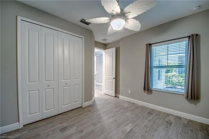 Guest Room featuring wood-finish flooring, a ceiling fan with integrated lighting, a window with horizontal blinds, and a bi-fold closet