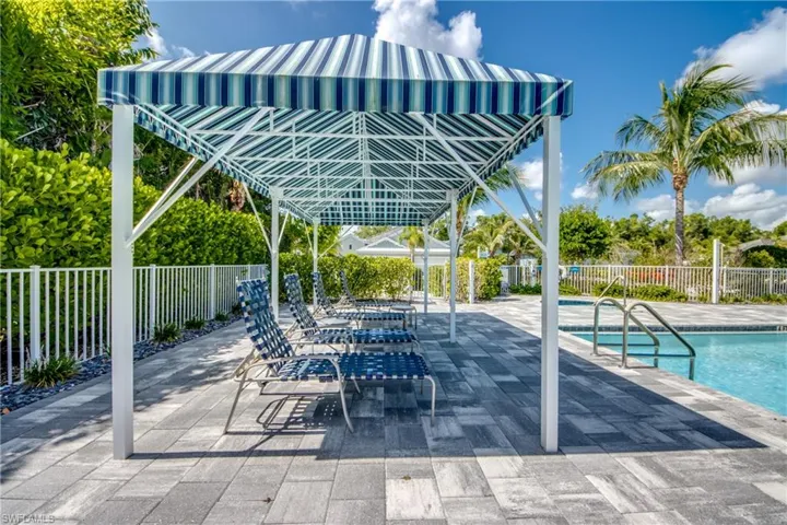 Covered community pool cabana area with seating and paver deck