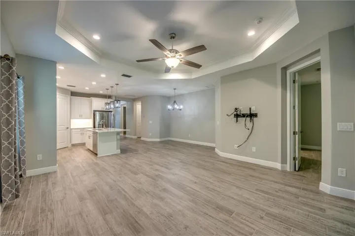 Open-concept living area featuring wood-finish tile flooring, recessed lighting, and a tray ceiling
