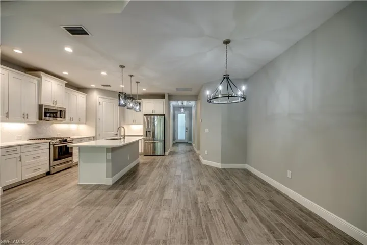 Open-concept kitchen with a large island with pendant lights and dedicated dining area