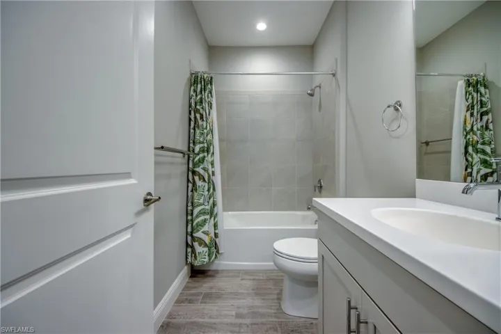 Full guest bathroom featuring a single vanity, integrated sink, and quartz countertop