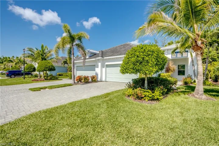 Exterior featuring brick paver driveway, and tropical landscaping with palm trees and shrubs